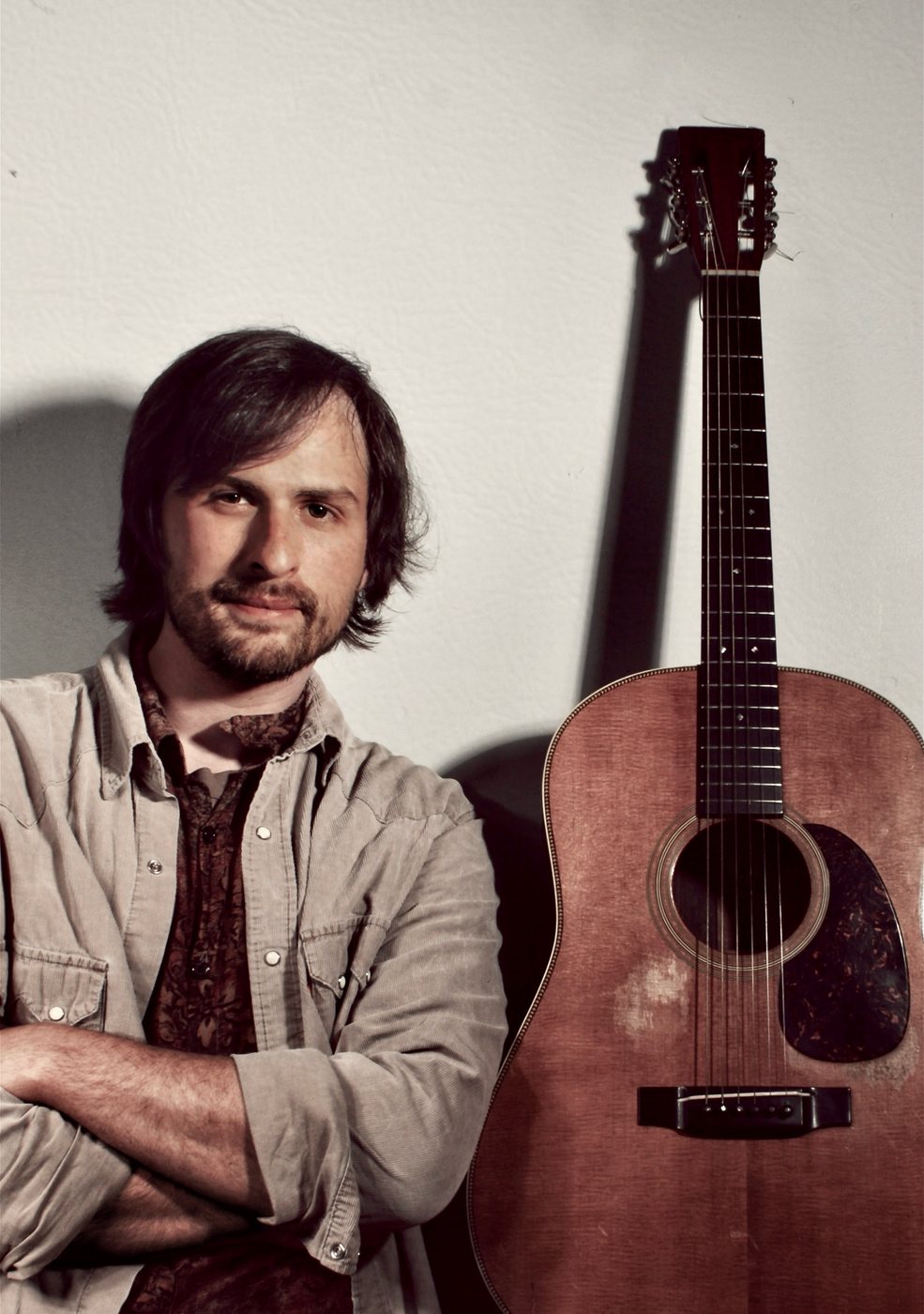 Roland Dixon with his acoustic guitar, arms crossed